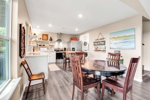 A modern kitchen with a dining area, white cabinetry, and a large window. - Westview Lookout | Panoramic Lake Views, Decks & Near Boat Ramp (Canyon Lake)