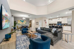 A modern living room with a sofa, chairs, a coffee table, and a dining area with a table and chairs. - Private Pool+Spa*Games Room*Clubhouse Amenities (Kissimmee)