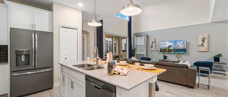 A modern kitchen with a central island, stainless steel appliances, and pendant lighting.