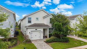 A residential building with a garage, a front yard with a pathway, and a clear blue sky. - Private Pool+Spa*Games Room*Clubhouse Amenities (Kissimmee)