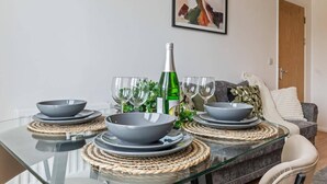 A dining table set with bowls, glasses, and a bottle, surrounded by woven placemats. - 2 Bed Apartment - Sleeps 5 - Parking - Wifi (Birmingham)