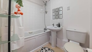 A bathroom with a bathtub, a sink, and a toilet. There is a glass shelf with a rubber duck on it. - 2 Bed Apartment - Sleeps 5 - Parking - Wifi (Birmingham)