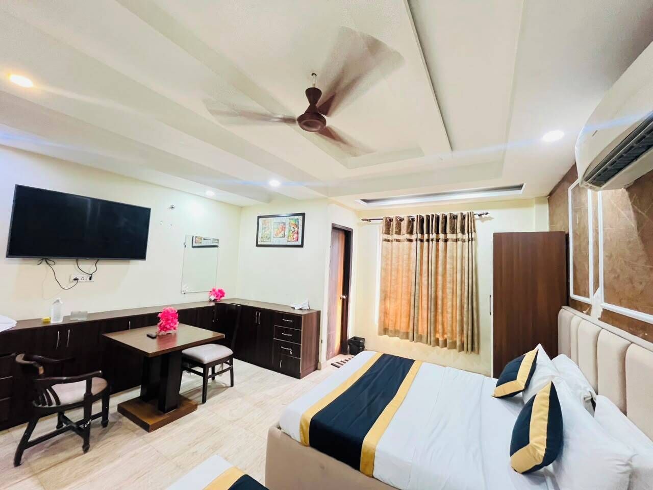 A hotel room with a bed, desk, chair, television, and a ceiling fan.