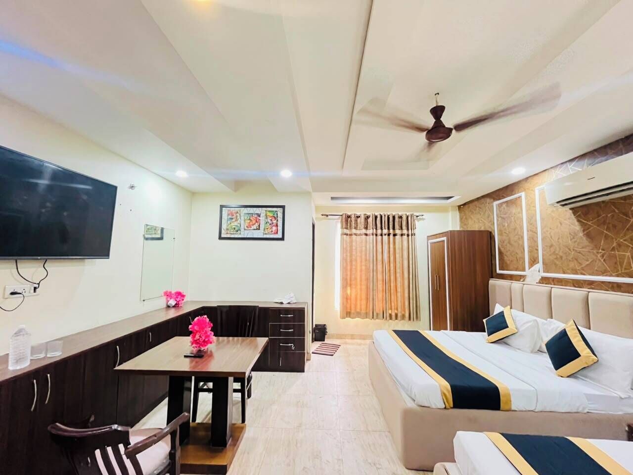 Une chambre d’hôtel équipée d’un lit, d’un bureau, d’une chaise, d’une télévision et d’un ventilateur de plafond.