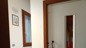 A hallway with a white door, a staircase, and a framed picture on the wall.