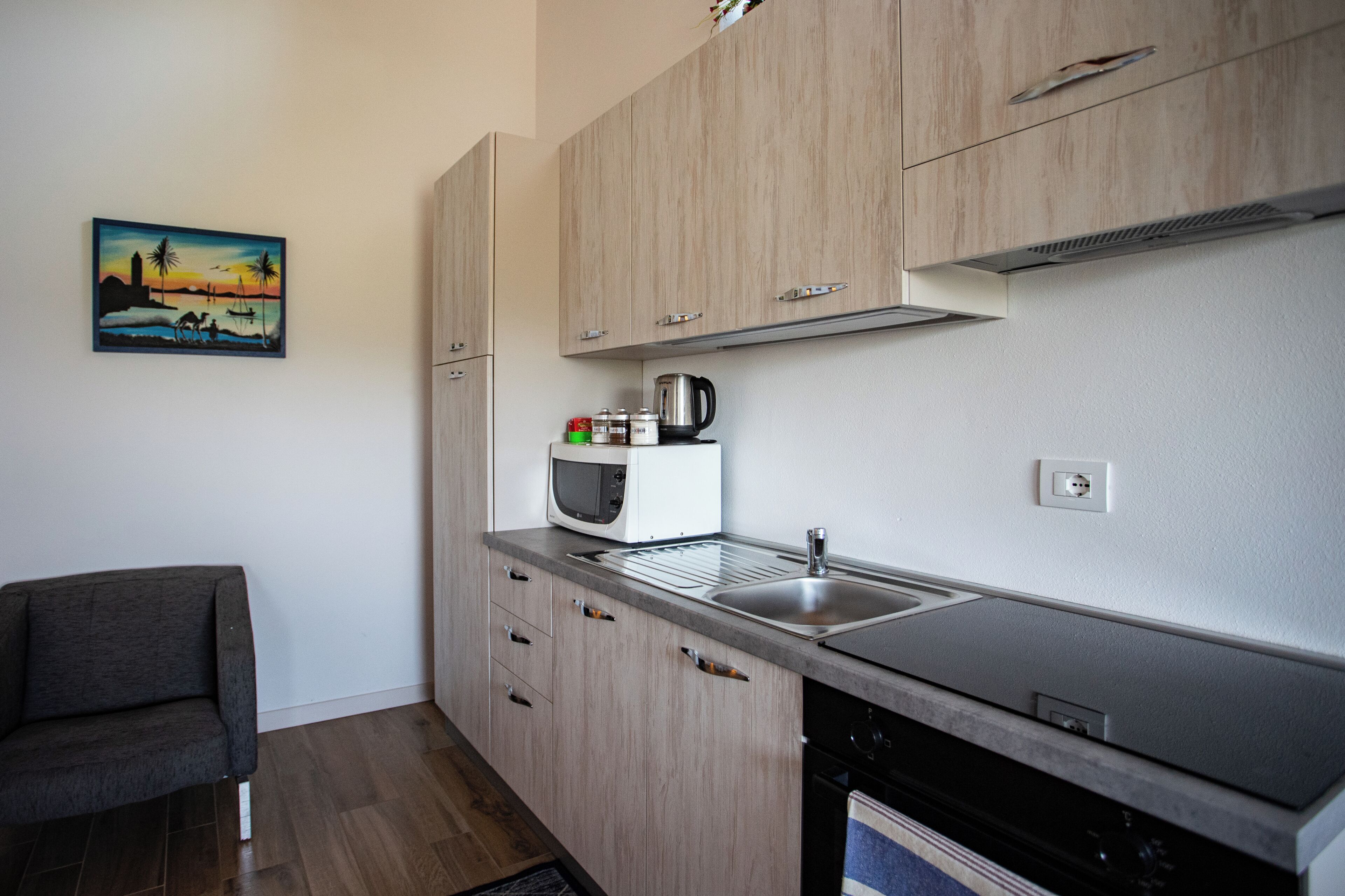 A modern kitchen with wooden cabinets, a stainless steel sink, and a microwave.