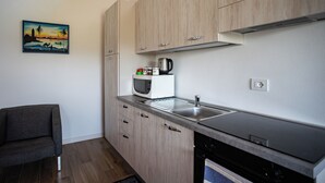 A modern kitchen with wooden cabinets, a stainless steel sink, and a microwave.