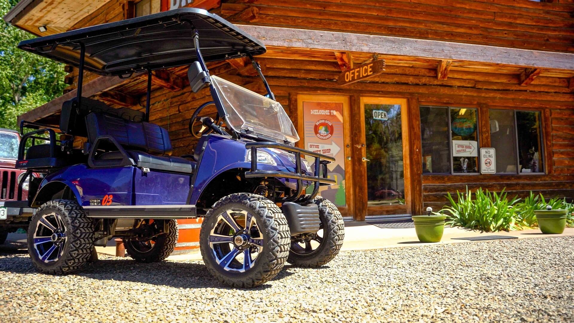 A blue golf cart parked in front of a wooden building with a sign reading 'OFFICE.'