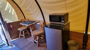 A compact kitchenette with a microwave, a small refrigerator, and a wooden table with chairs.
