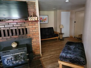 Ein Wohnzimmer mit Kamin, Fernseher, Sofa, Lampe und einer Tür.
