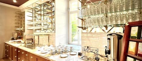 A kitchen with a marble countertop, glassware storage, and a coffee machine.