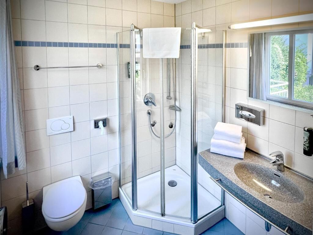 Een badkamer met een douchecabine van glas, een wastafel en een toilet.