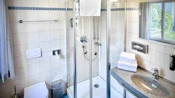 Une salle de bain avec une douche à parois de verre, un lavabo et des toilettes.