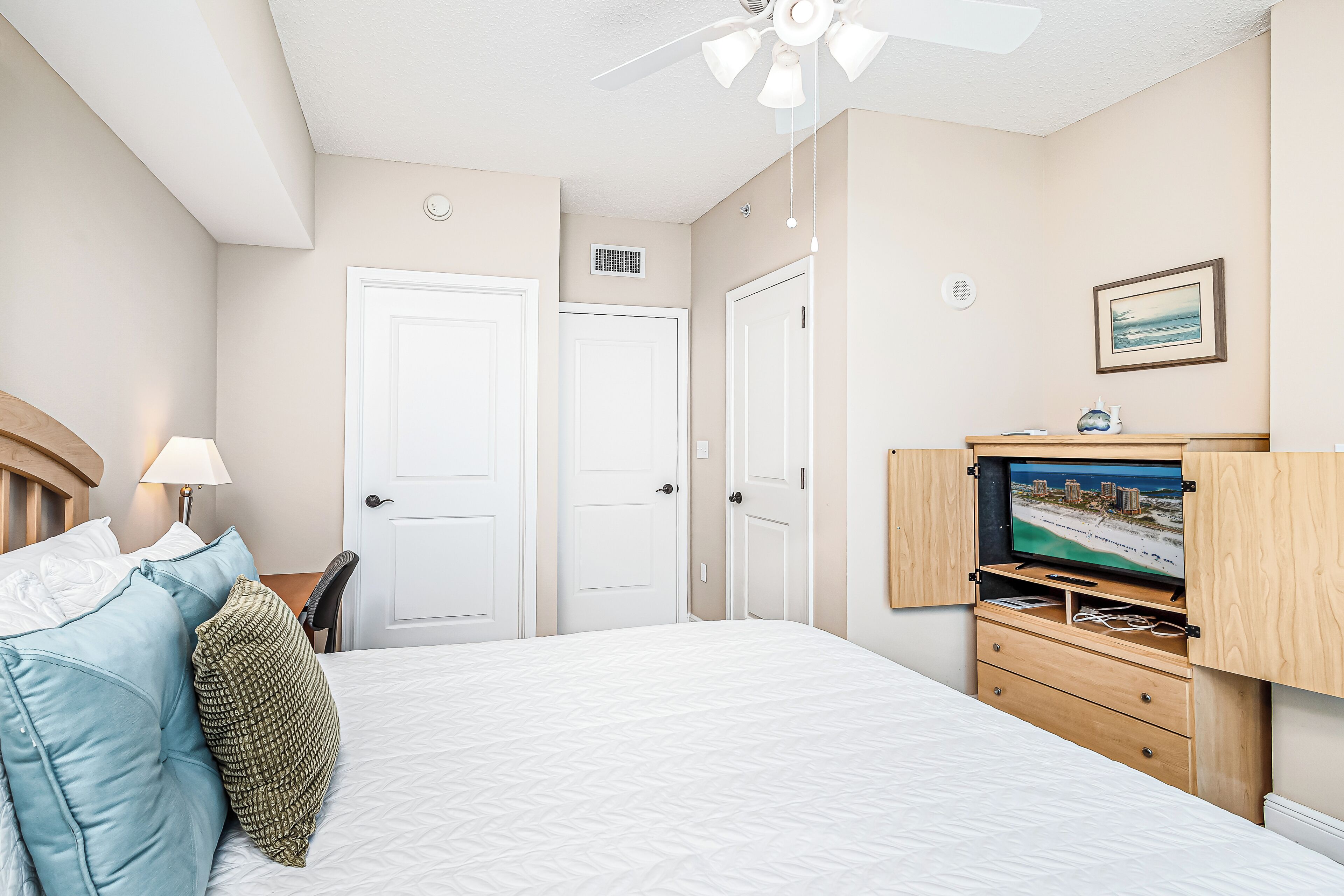 A hotel room with a bed, a TV, a desk, and a chair.