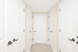 A corridor with white doors and a beige floor. - Portofino Tower 3-1009 | Gulf Views & Steps to the Beach (Pensacola Beach)