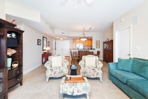 A living room with two armchairs, a sofa, a coffee table, and a dining area with a table and chairs. - Portofino Tower 3-1009 | Gulf Views & Steps to the Beach (Pensacola Beach)