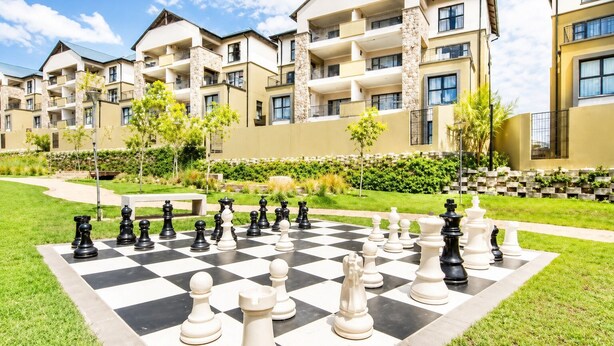 A chessboard set up in a courtyard with apartment buildings in the background. - Lovely 1-bedroom apartment in Waterfall Midrand. (Waterfall, Midrand)