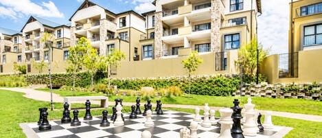 A chessboard set up in a courtyard with apartment buildings in the background.