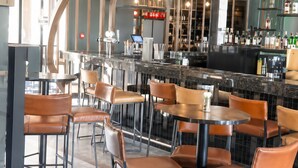 A modern bar area with leather chairs, a curved counter, and a display of bottles. - Lovely 1-bedroom apartment in Waterfall Midrand. (Waterfall, Midrand)