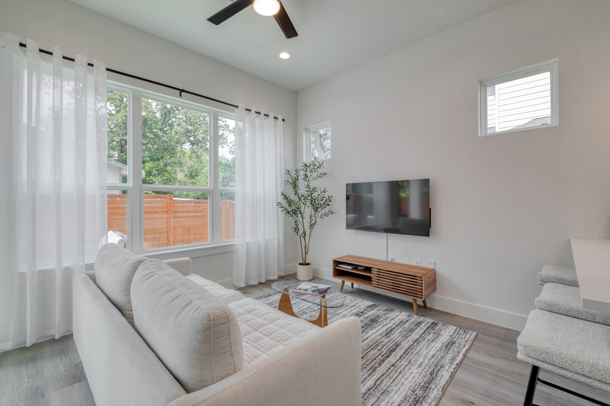 A modern living room with a sofa, TV, and a potted plant.