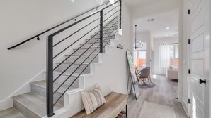 Eine Treppe mit Metallgeländer, einer Holzbank und einem Teppich auf einem Holzboden.