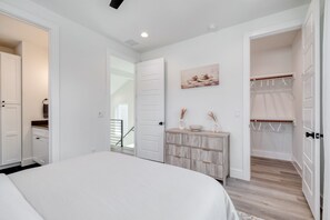 A bedroom with a bed, a dresser, a closet, and a staircase leading to another room. - Luxury New Build with 2 Ensuite Suites & Private Backyard Near UT & Downtown (Austin)