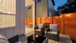 Eine Terrasse mit Korbmöbeln, einem Tisch mit Kerze und einem Holzzaun.