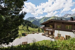 A mountain lodge with a patio area, a sign reading 'Hofstuben,' and a view of mountains in the background. - Berggasthaus Höllensteinhütte (Tux)
