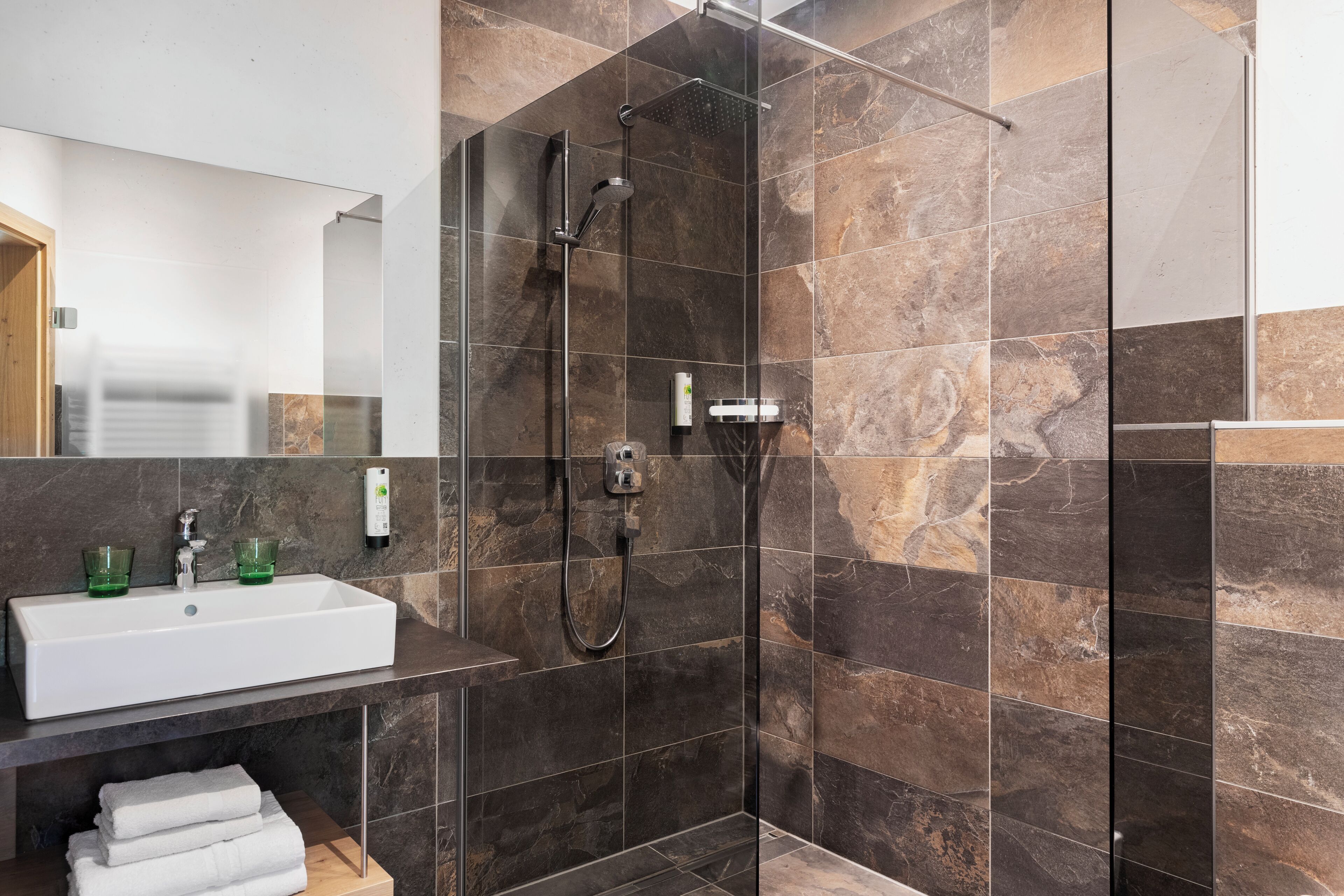 A modern bathroom with a glass-enclosed shower, a white sink, and a mirror.