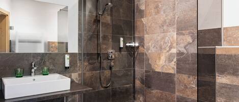A modern bathroom with a glass-enclosed shower, a white sink, and a mirror.