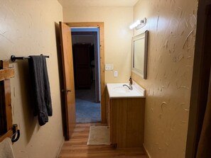 Une petite salle de bain avec une porte en bois, un lavabo et un porte-serviettes.