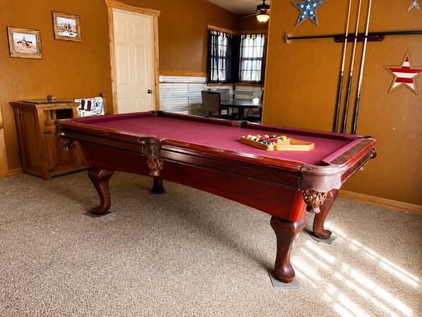Une table de billard recouverte d’un drap de feutre rouge, avec un jeu de billes.