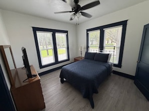 A bedroom with a bed, a dresser, a ceiling fan, and two windows with blinds. - Built for Work Crews & Extended Business Stays. (Gainesville)