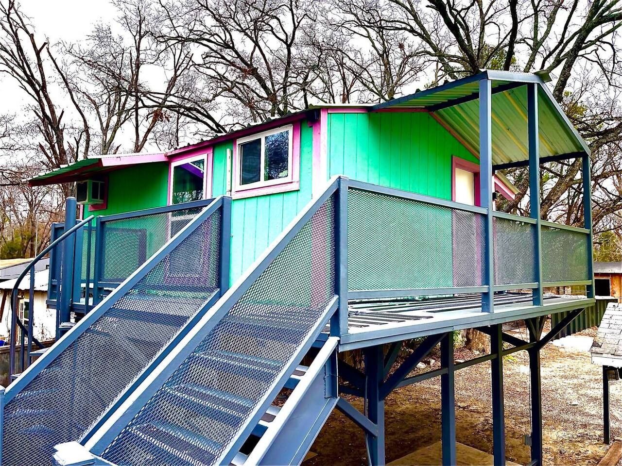 Eine mehrstöckige Außenanlage mit einer Metalltreppe und einem Gebäude mit einem grünen Anbau und einem rosafarbenen Dach.