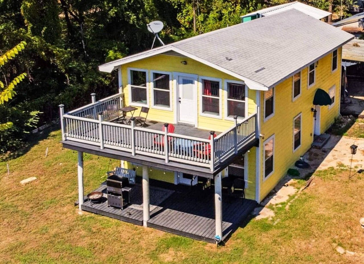 Une maison jaune à deux étages, dotée d’un balcon, d’une antenne parabolique et d’une terrasse.