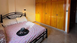 Une chambre à coucher avec un lit, une armoire et un luminaire fixé au plafond.