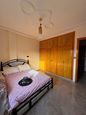 A bedroom with a bed, wardrobe, and a ceiling light fixture. - Beachfront Apartment in Saidia (Saïdia)