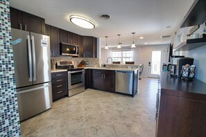 A modern kitchen with stainless steel appliances, dark cabinetry, and a central island. - Grove City Serenity Englewood FL
10 minutes to Englewood Beach (Grove City)