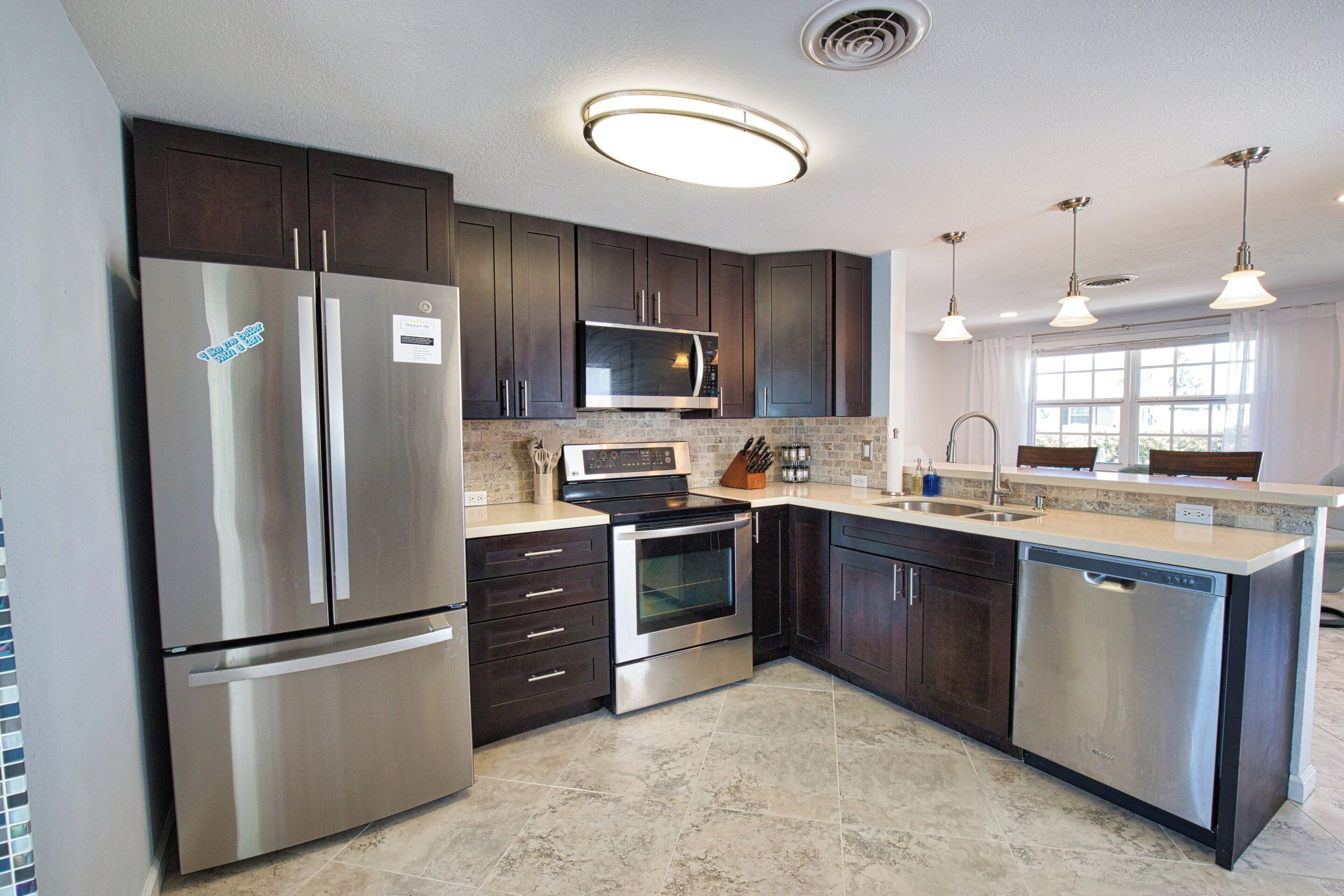 A modern kitchen with stainless steel appliances, dark wood cabinets, and a large island with a sink.