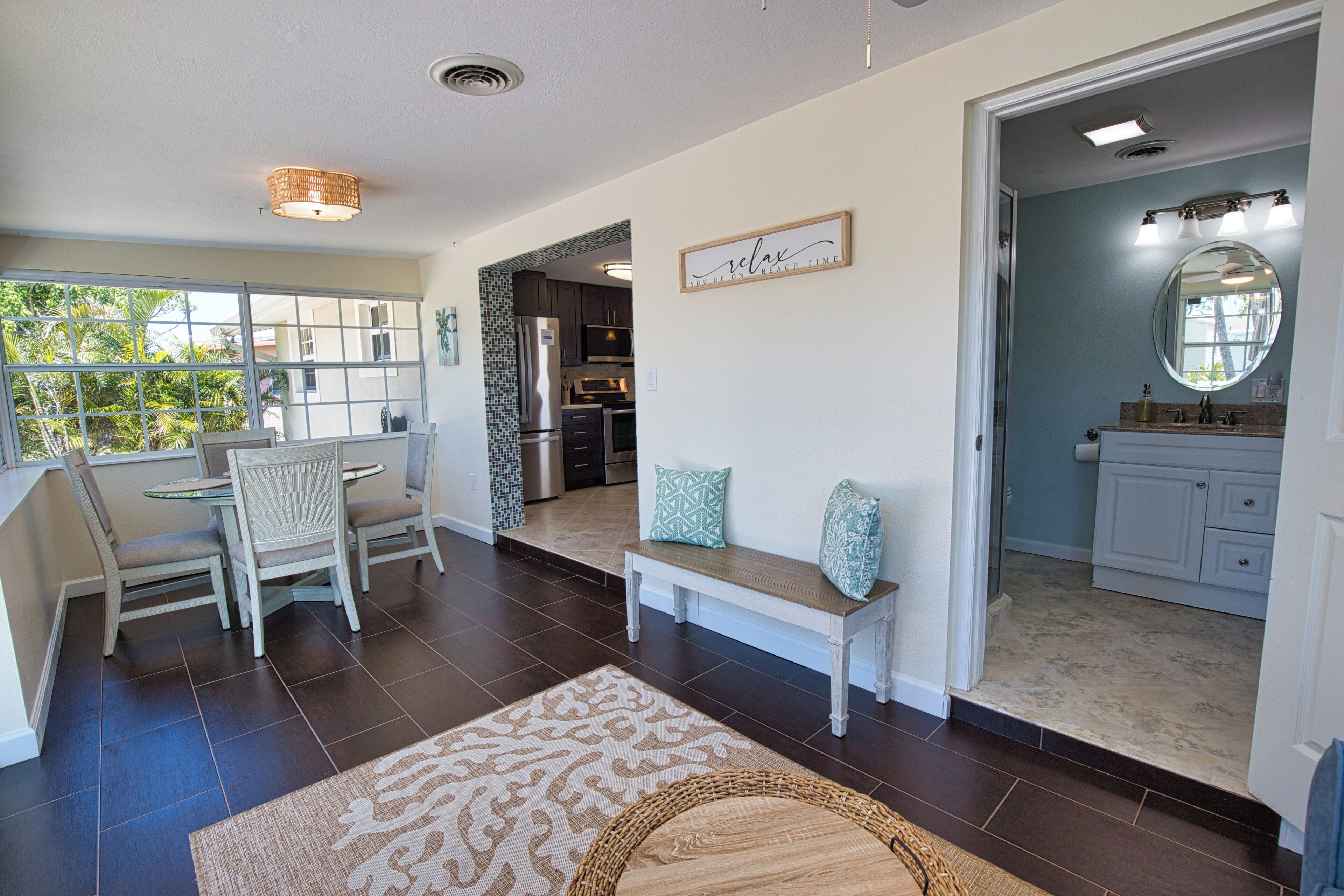 A spacious living area with a dining set, a kitchen with modern appliances, and a bathroom with a large mirror.