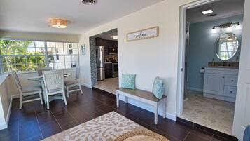 A spacious living area with a dining set, a kitchen with modern appliances, and a bathroom with a large mirror.