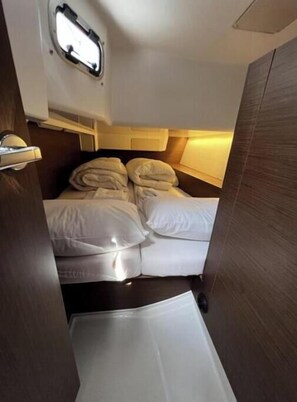 A compact, well-lit cabin with a small bed, a window, and a wooden wall. - Oceanis 34.1 - Clara (Bibinje)