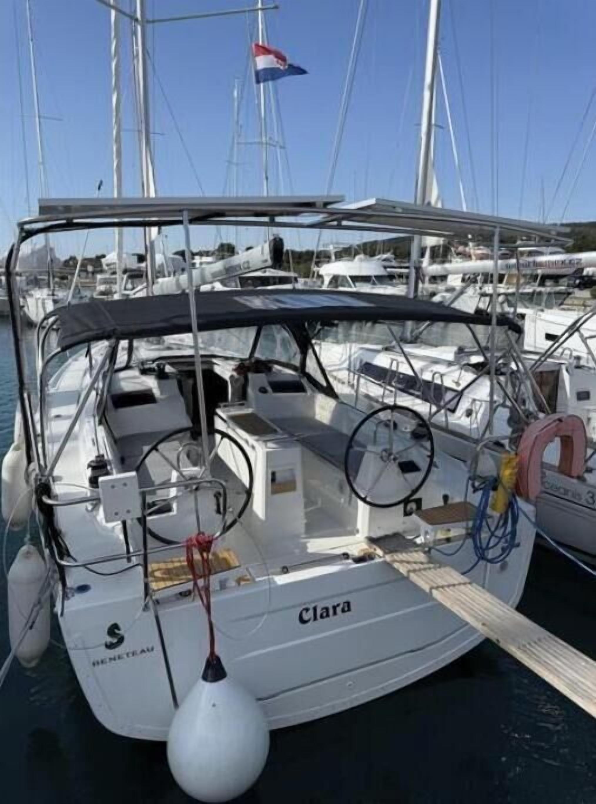 A sailboat named 'Clara' docked at a marina with other boats.