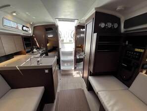 A compact RV interior with a kitchenette, a dining area, and a small living space. - Oceanis 34.1 - Clara (Bibinje)