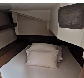 A bunk bed with a headboard, a pillow, and a wooden headboard on the left. - Oceanis 34.1 - Navicela (Medulin)
