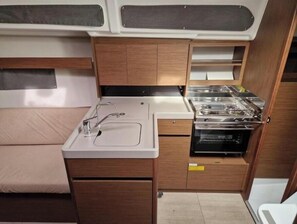 A compact kitchenette with a sink, stove, and storage cabinets. - Oceanis 34.1 - Navicela (Medulin)
