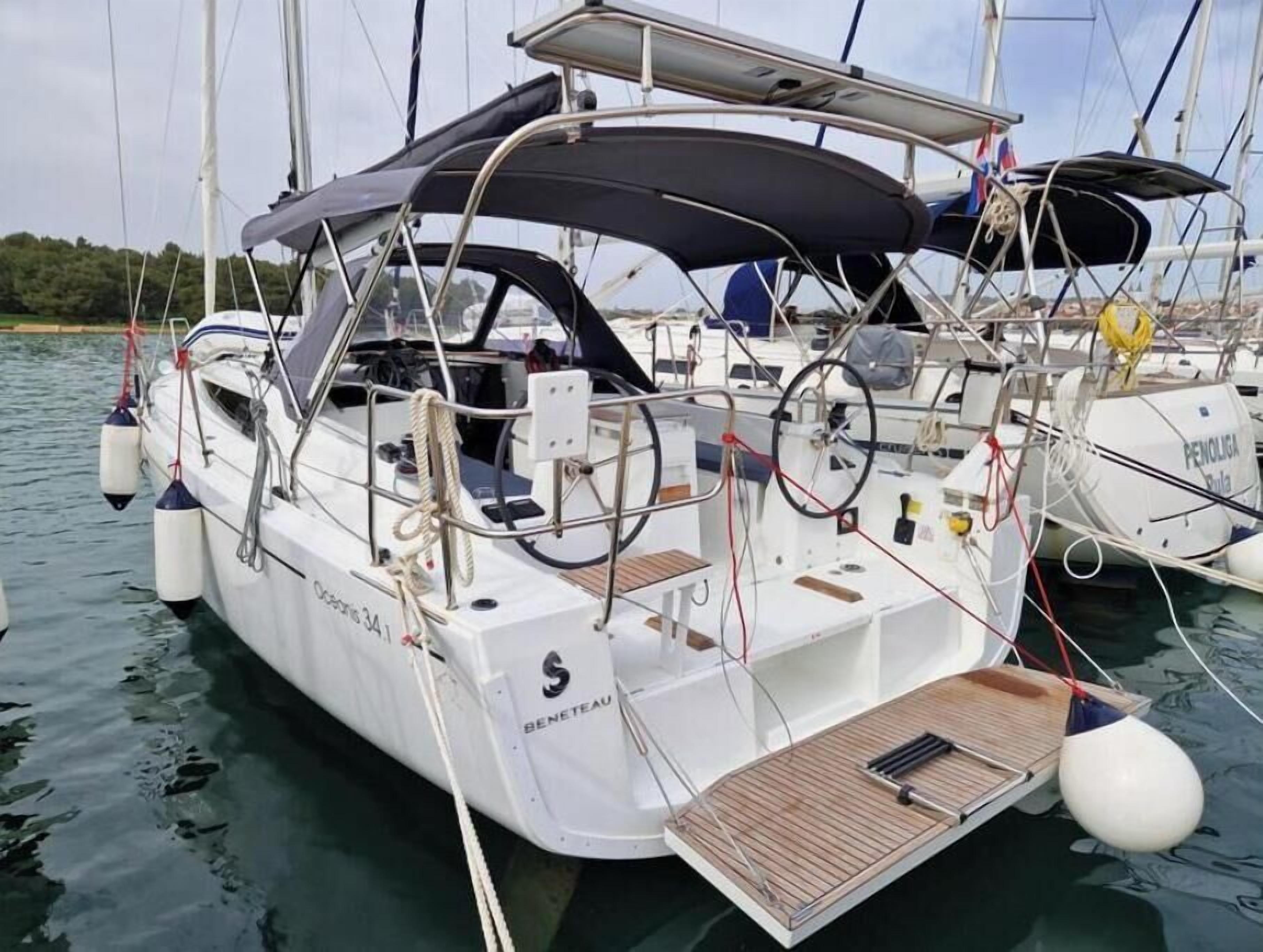 Een zeilboot met een afdak, genaamd 'BENETEAU', afgemeerd in rustig water.
