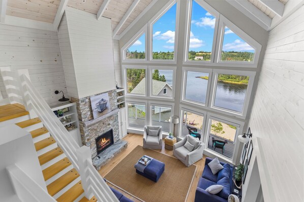 A spacious living room with a fireplace, large windows, and a view of a lake.