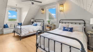 Ein Schlafzimmer mit zwei Betten, einem Deckenventilator und Blick ins Freie.