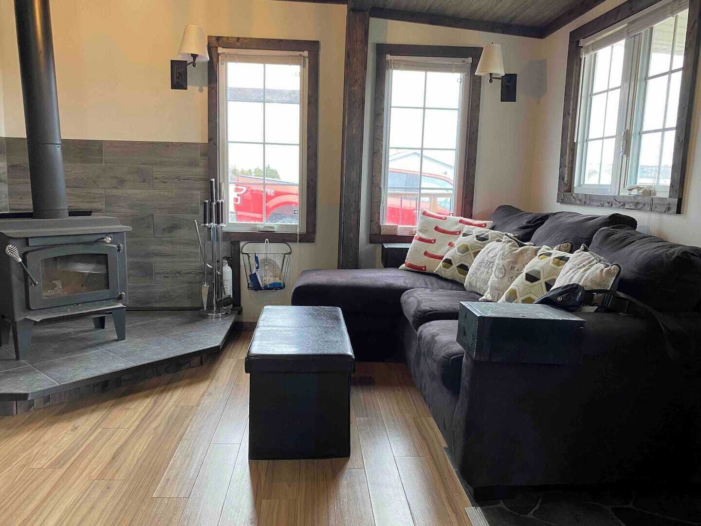 Ein gemütliches Wohnzimmer mit Kaminofen, einer Couch und einem kleinen Tisch.